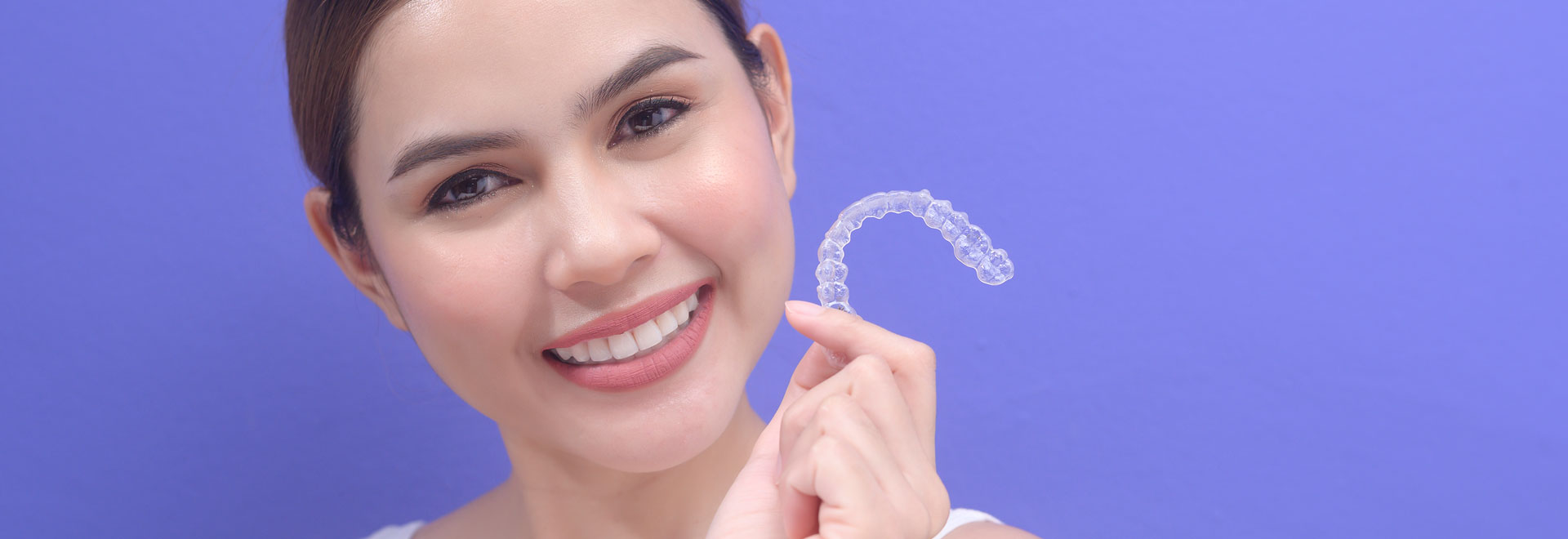 A young woman holding invisalign braces